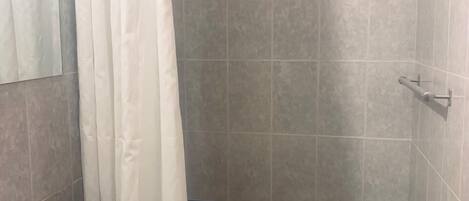 A bathroom with a shower, a sink, and tiled walls.