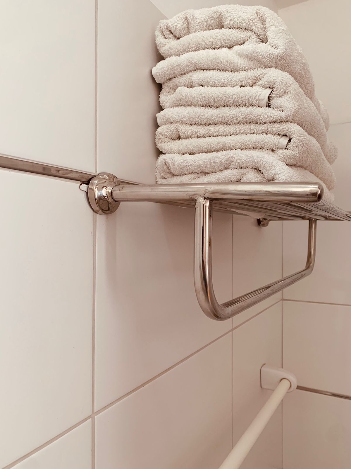 A bathroom with a towel rack holding neatly folded towels.