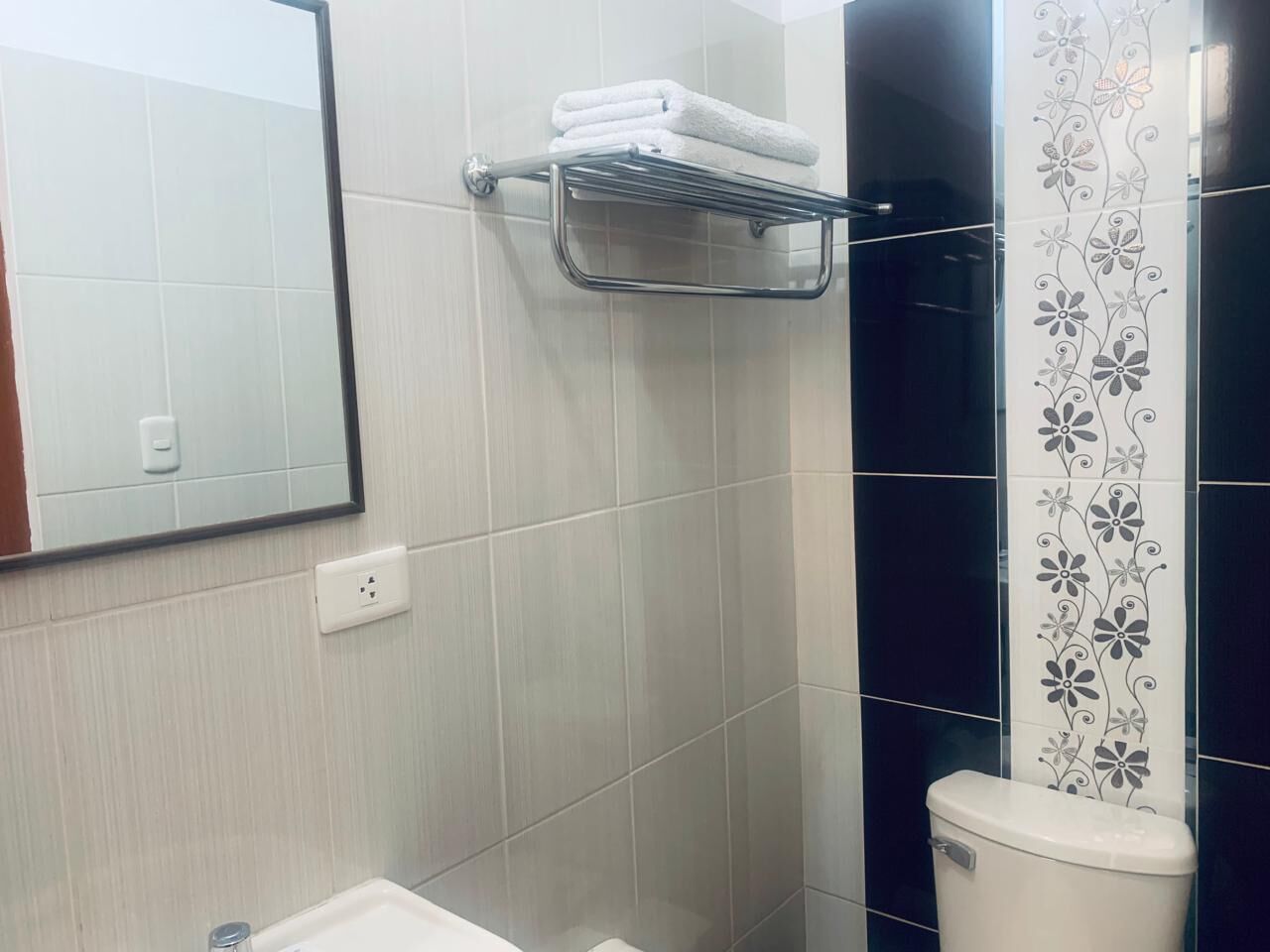 A bathroom with a white sink, a mirror, a towel rack, and a toilet.