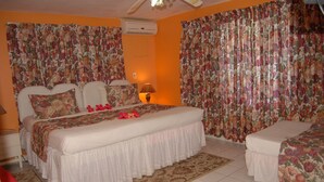 A bedroom with a bed, bedside tables, a lamp, and curtains. - PinkHibiscus Guest House (Montego Bay)