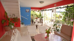 A patio area with white furniture, a round table, and potted plants. - PinkHibiscus Guest House (Montego Bay)