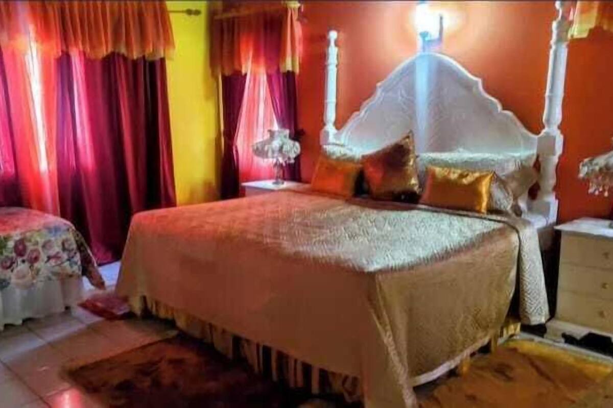 A bedroom with a four-poster bed, a nightstand, and a bedside table.