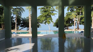 Un espacio al aire libre cubierto con vista a la playa y palmeras.