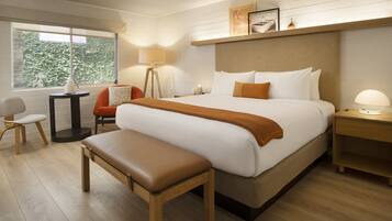 Una habitación de hotel con una cama grande, un banco, un escritorio y una silla.