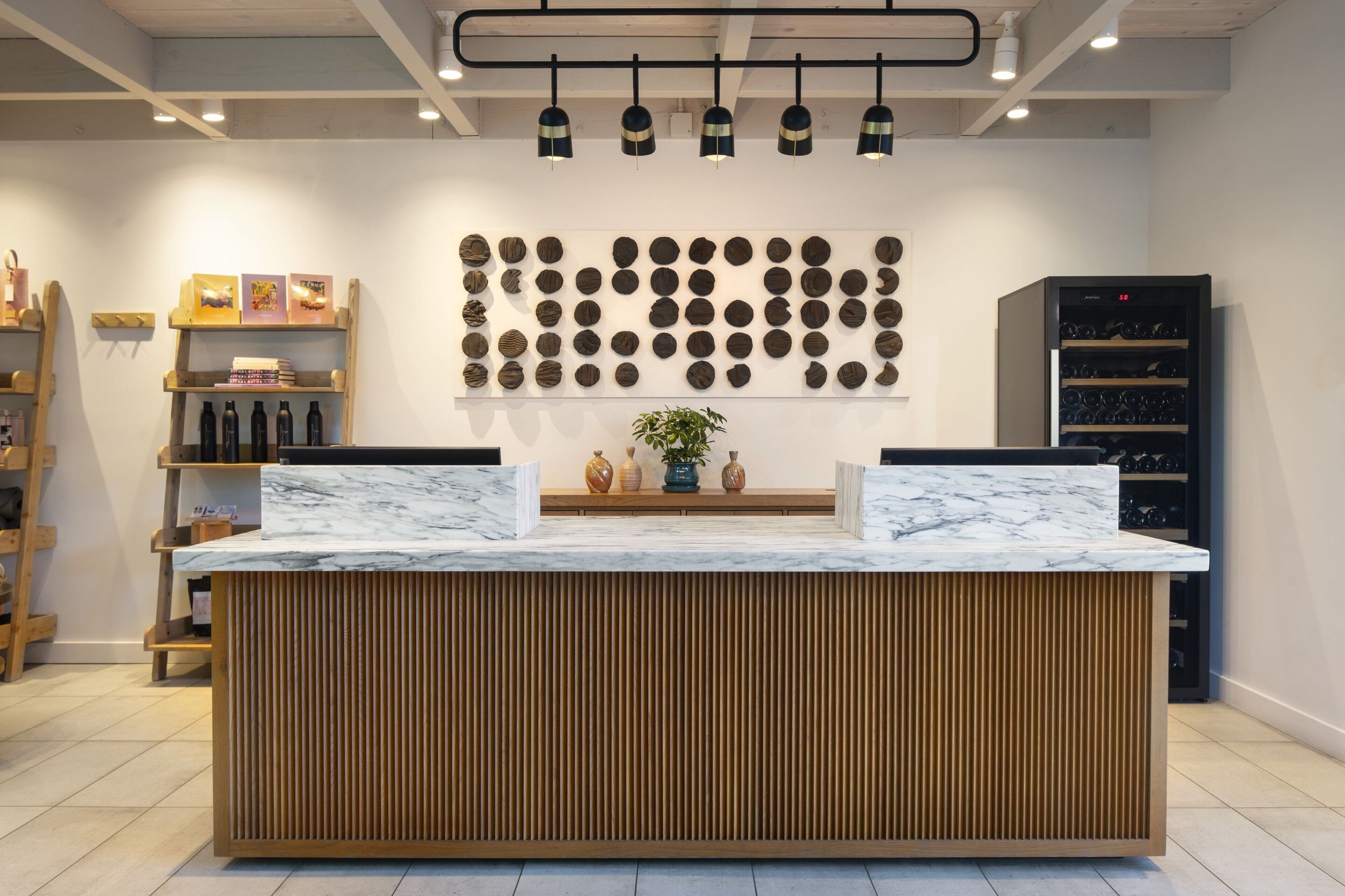 A reception desk with a marble top, wooden paneling, and a wall of circular decorative items above.
