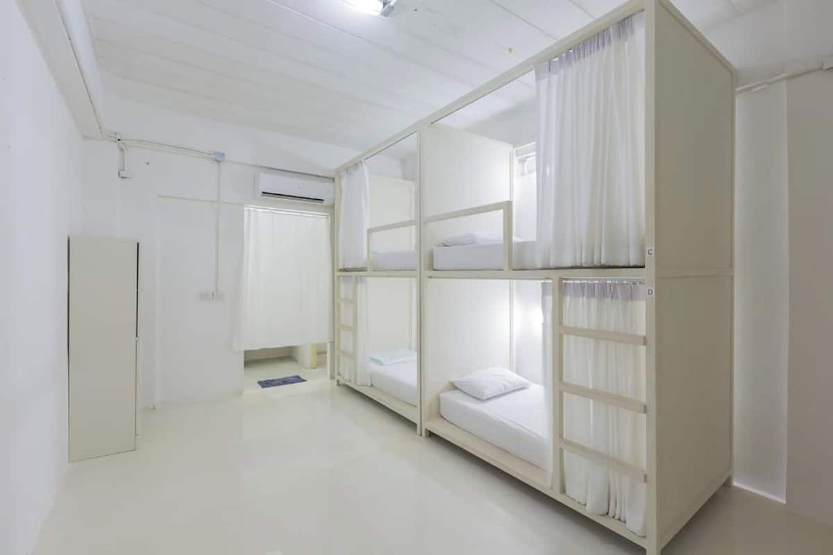 A dormitory room with bunk beds, a wardrobe, and a door.