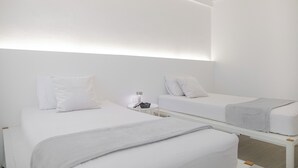 A modern hotel room with two beds, a bedside table, and a nightstand. - HAO HOSTEL PHUKET (Phuket)