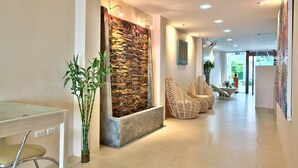 Un vestíbulo moderno con pared de piedra, zona de estar y mesa de vidrio.