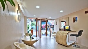 Un interior moderno con una recepción, dos mesas redondas y una zona de bar.