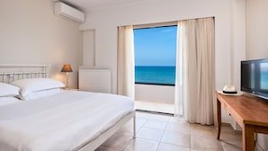 Habitación de hotel con cama, televisión, mesa, lámpara y vistas al mar.