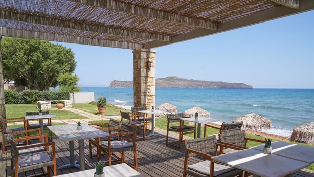 Un patio al aire libre con mobiliario de madera y vista al mar.