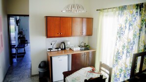 A compact kitchen with wooden cabinets, a small refrigerator, and a coffee maker. - Yiannis Apartments (Kos)