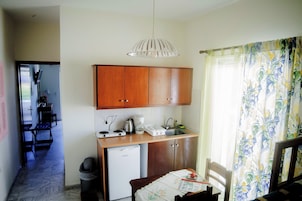 Una cocina compacta con armarios de madera, un refrigerador pequeño y una cafetera.