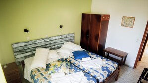 A bedroom with a wooden bed, two bedside tables, a wardrobe, and a map on the wall. - Yiannis Apartments (Kos)