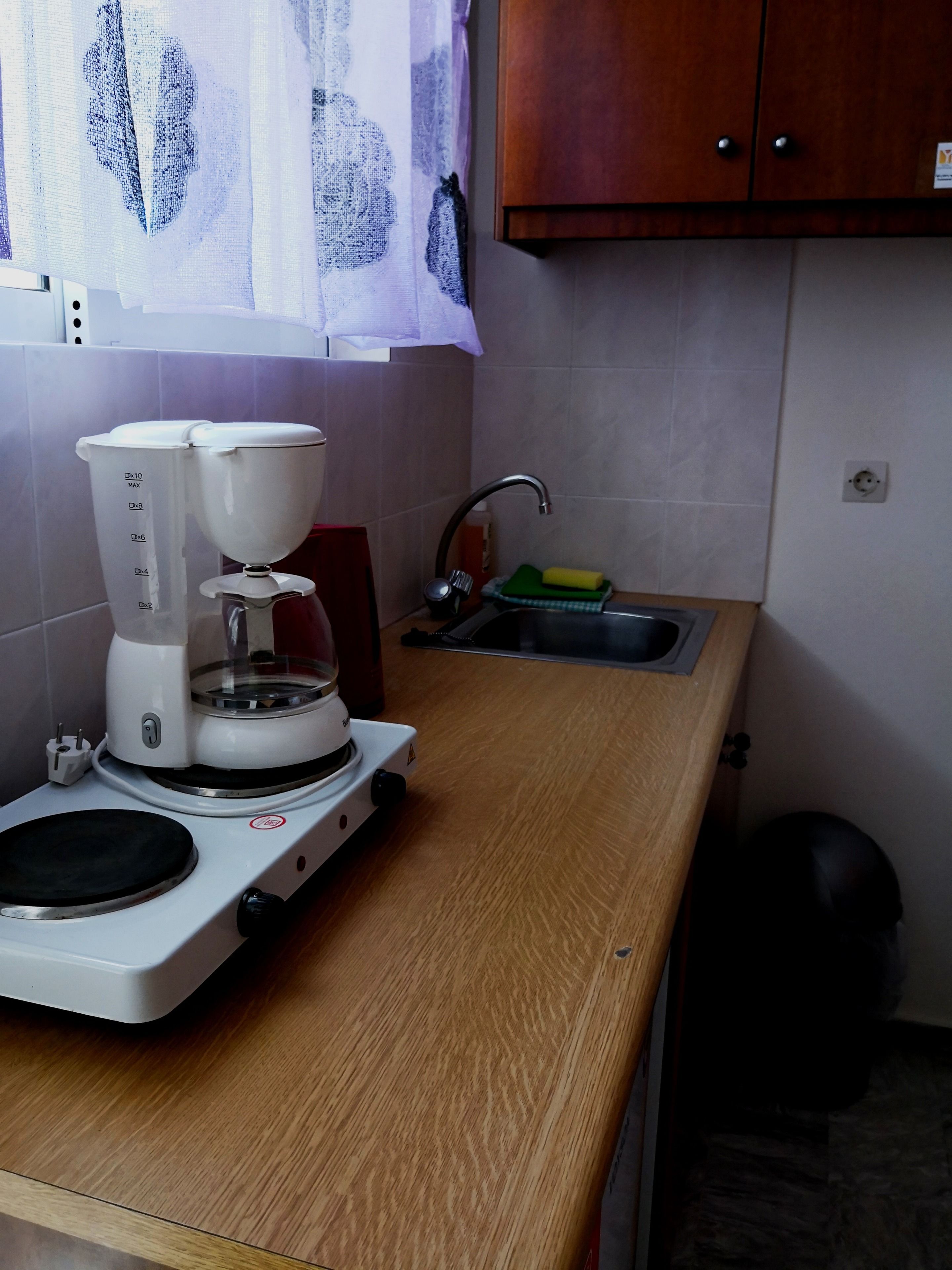 Una cocina con cafetera, un lavabo y un armario.