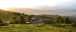 A rural landscape with a stone house surrounded by green fields and trees. - Agriturismo L'A Ceccoli (Sassofeltrio)