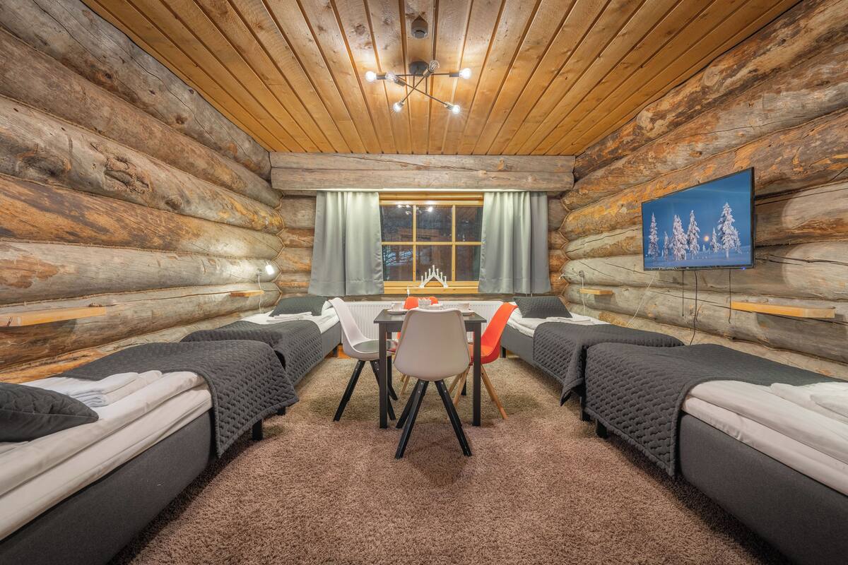 Une chambre de style rustique avec deux lits, une table à manger et un téléviseur fixé au mur.