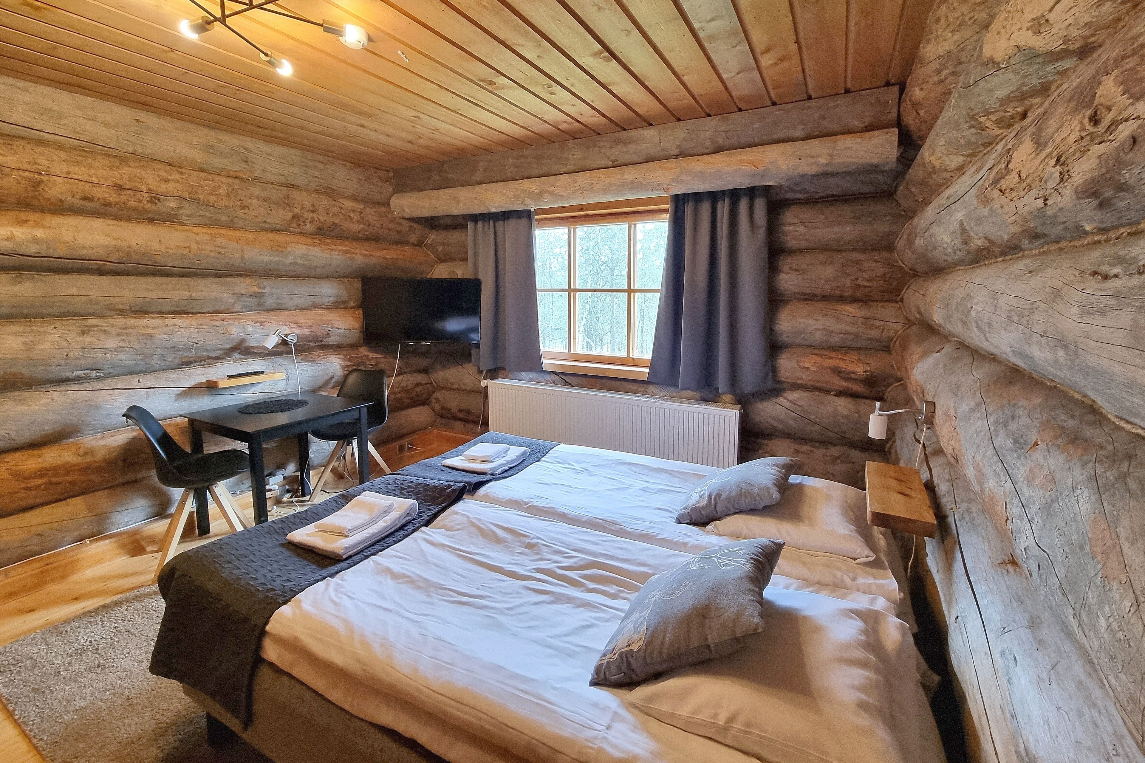 Une chambre aménagée dans un chalet en rondins, avec un lit, un bureau et un téléviseur.
