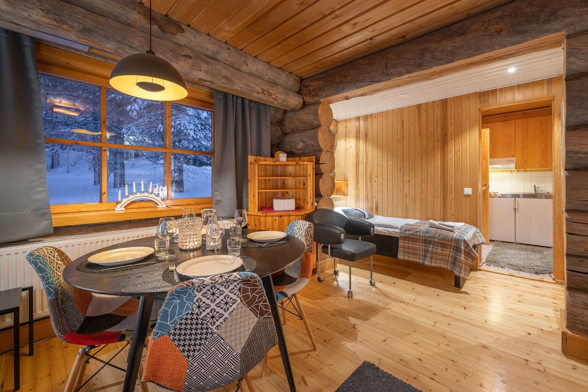 L’intérieur d’un chalet en bois chaleureux et accueillant, comprenant un coin repas, un lit et une cuisine.