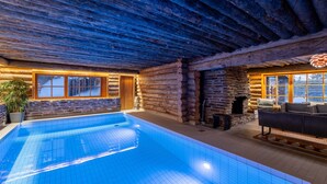 Une piscine intérieure avec un plafond en bois et des murs en pierre.