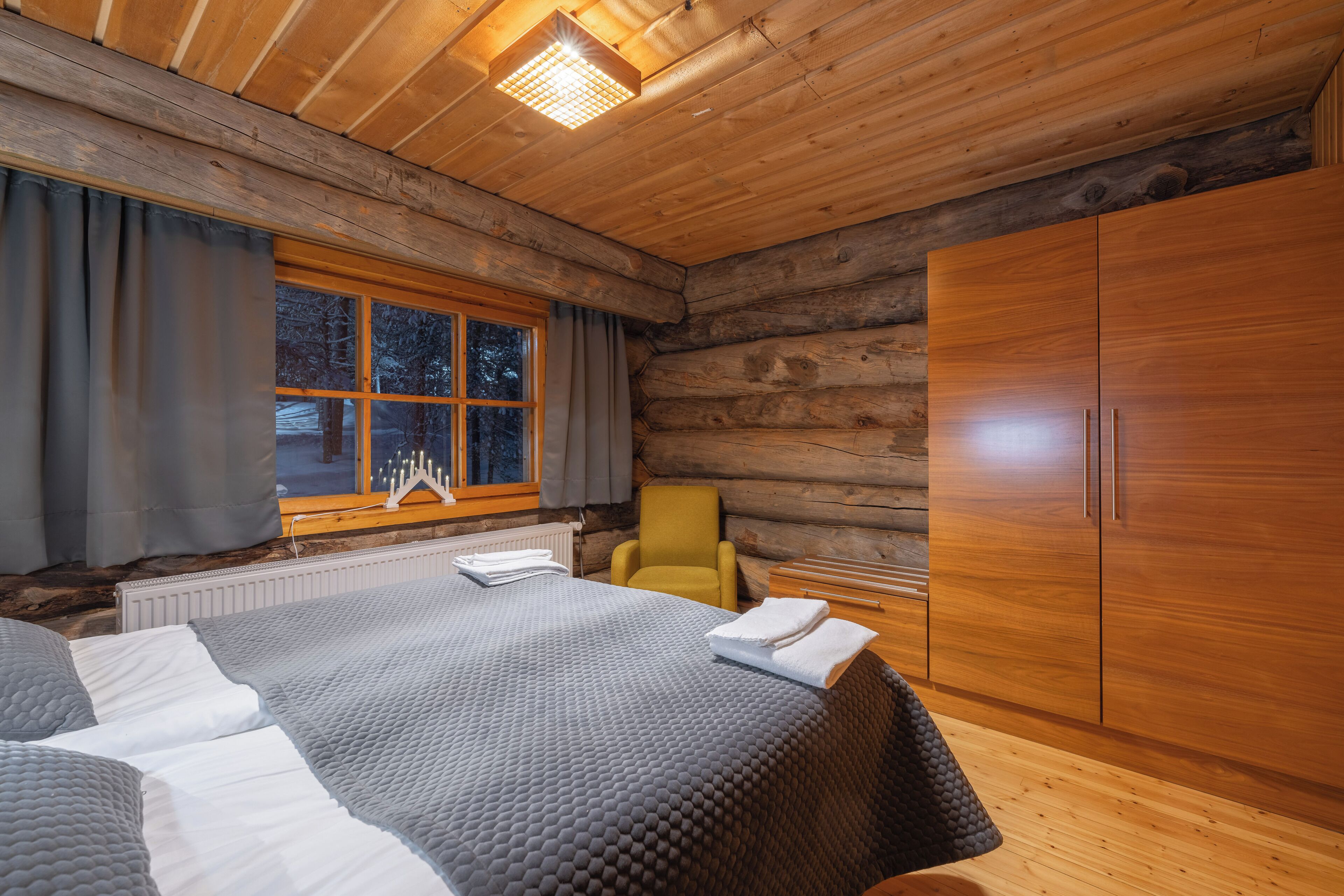 A log cabin room with a bed, a chair, and a wardrobe.