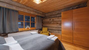 A log cabin room with a bed, a chair, and a wardrobe.