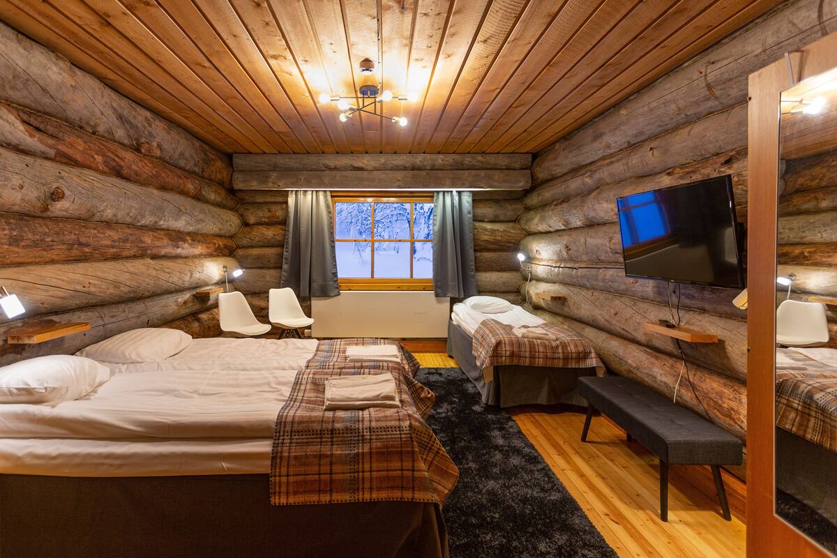 Une chambre de style rustique avec deux lits, une télévision et une fenêtre avec des rideaux.