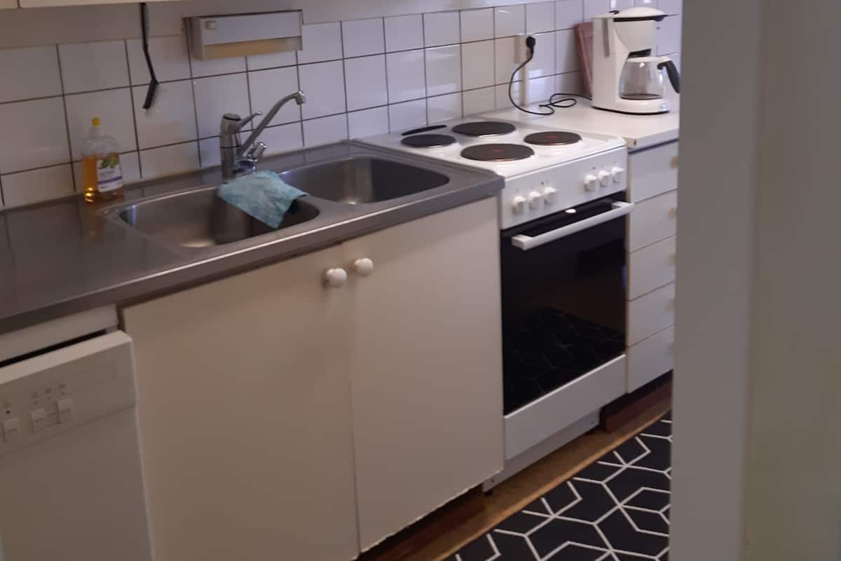 A kitchen with white cabinets, a stainless steel sink, a stove, and a coffee maker.