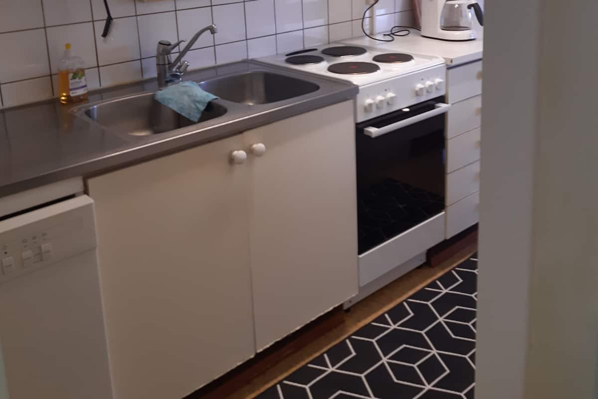A kitchen with white cabinets, a stainless steel sink, a stove, and a coffee maker.