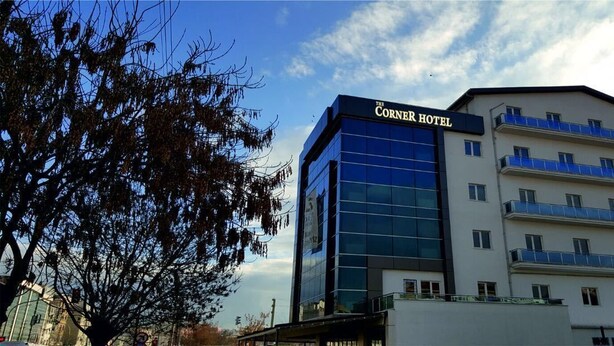 Um hotel com fachada de vidro moderna e uma placa com a inscrição "The Corner Hotel".