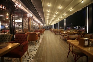 A restaurant with a long counter and multiple tables and chairs. - The Corner Hotel (Sincan)