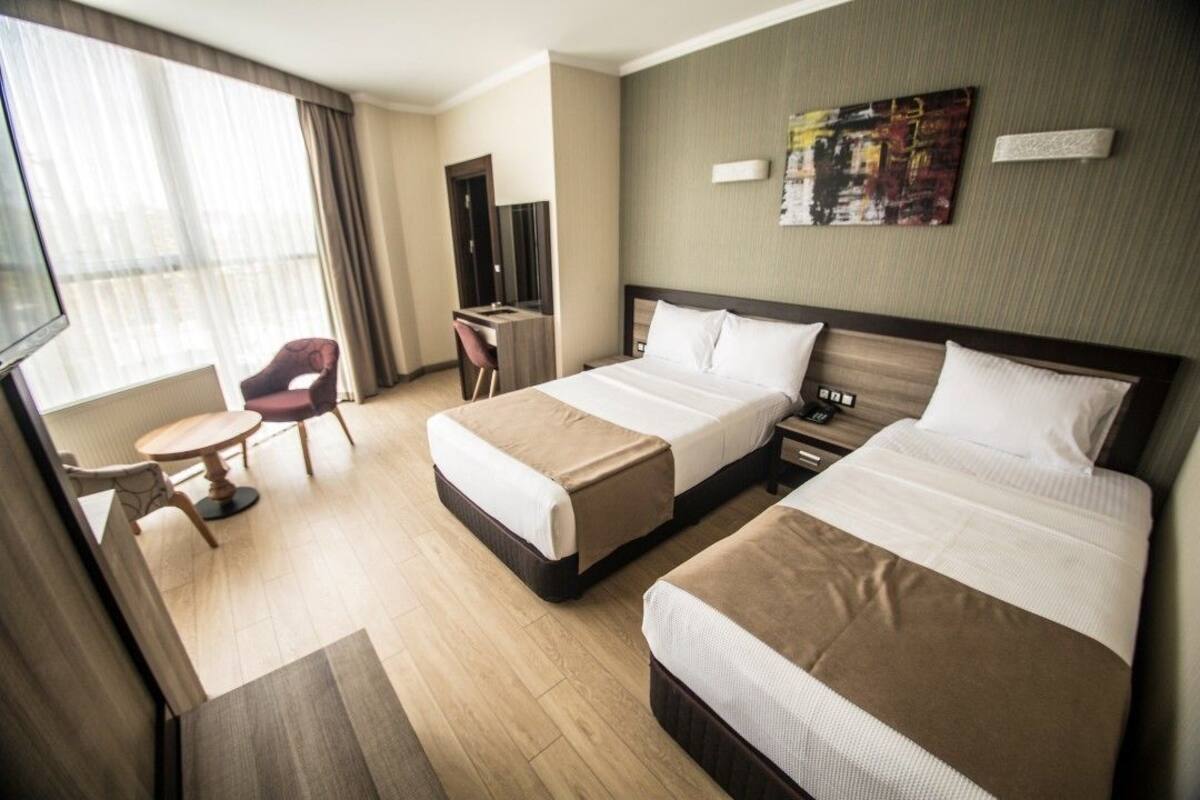 Habitación de hotel con dos camas, un escritorio, una silla y un televisor.