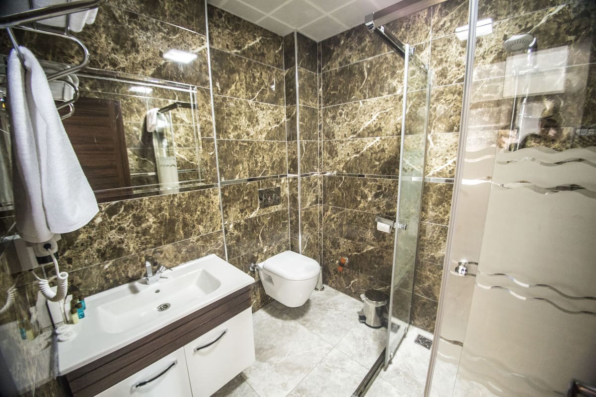 Un baño moderno con lavamanos de mármol, inodoro y cabina de ducha de vidrio.