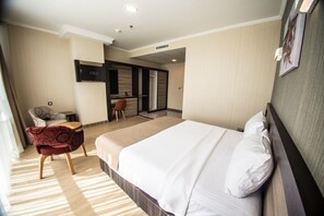 A hotel room with a large bed, a desk, a chair, and a small kitchenette. - The Corner Hotel (Sincan)