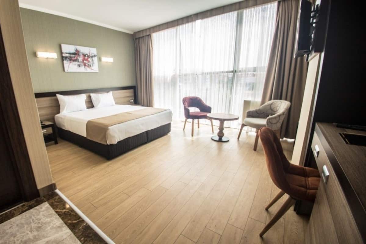 Una habitación de hotel con una cama grande, un escritorio, dos sillas y un televisor.