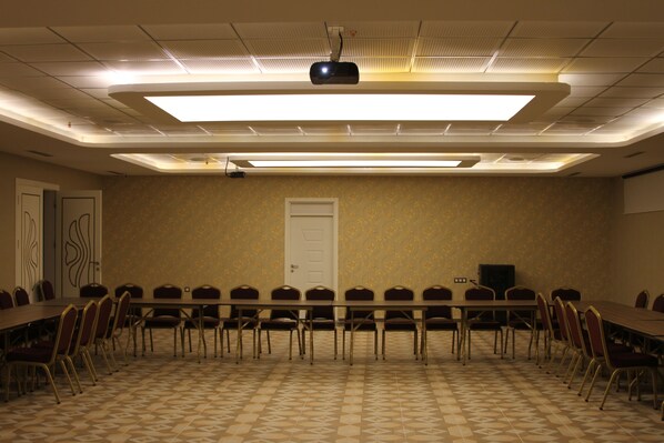 A conference room with a long table, chairs, a projector, and a door.