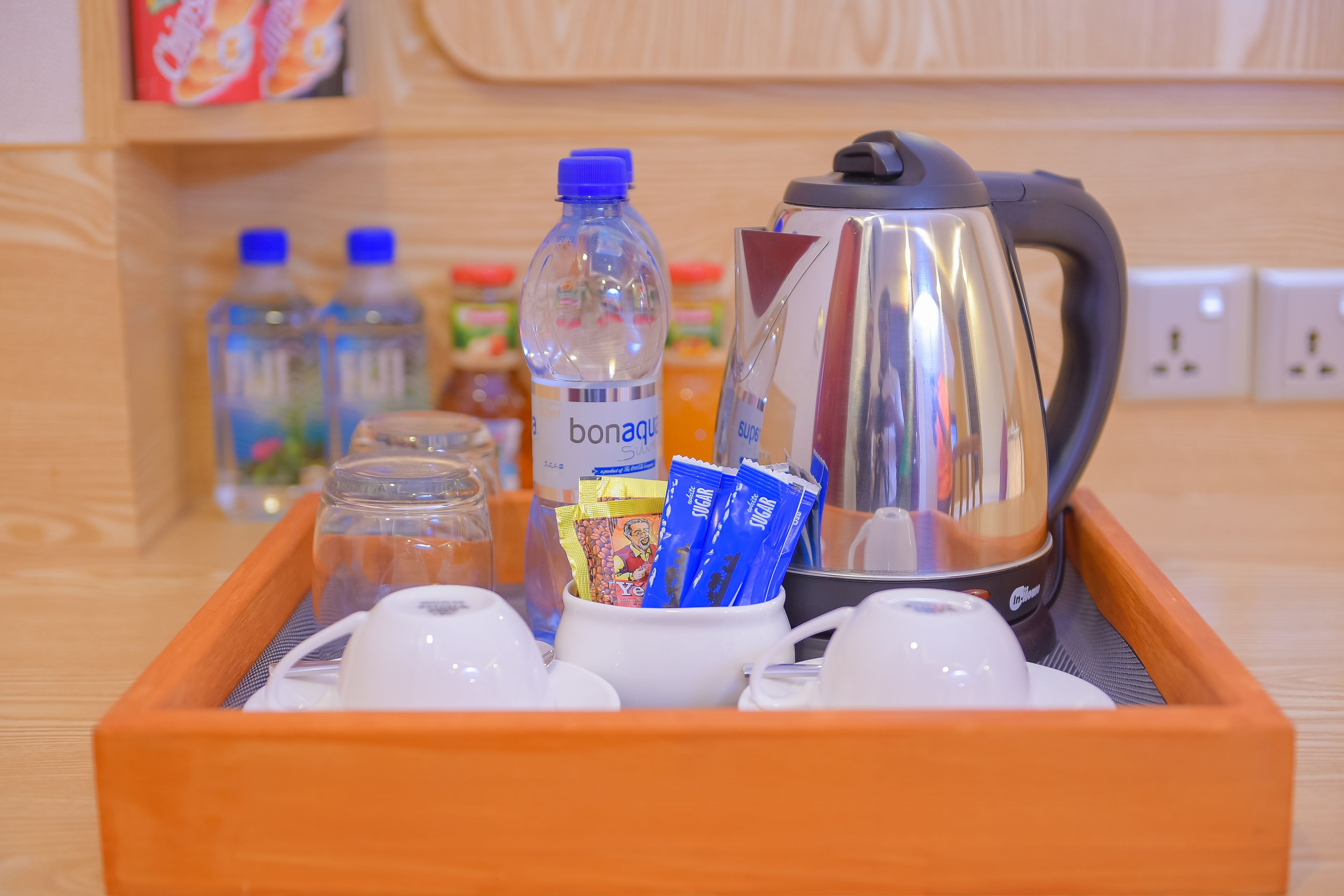 A tray with a bottle of water, a coffee maker, and several packets of sugar and tea.