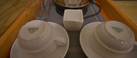 A tray with two white cups and a small white container, likely for cream or sugar, on a textured mat.