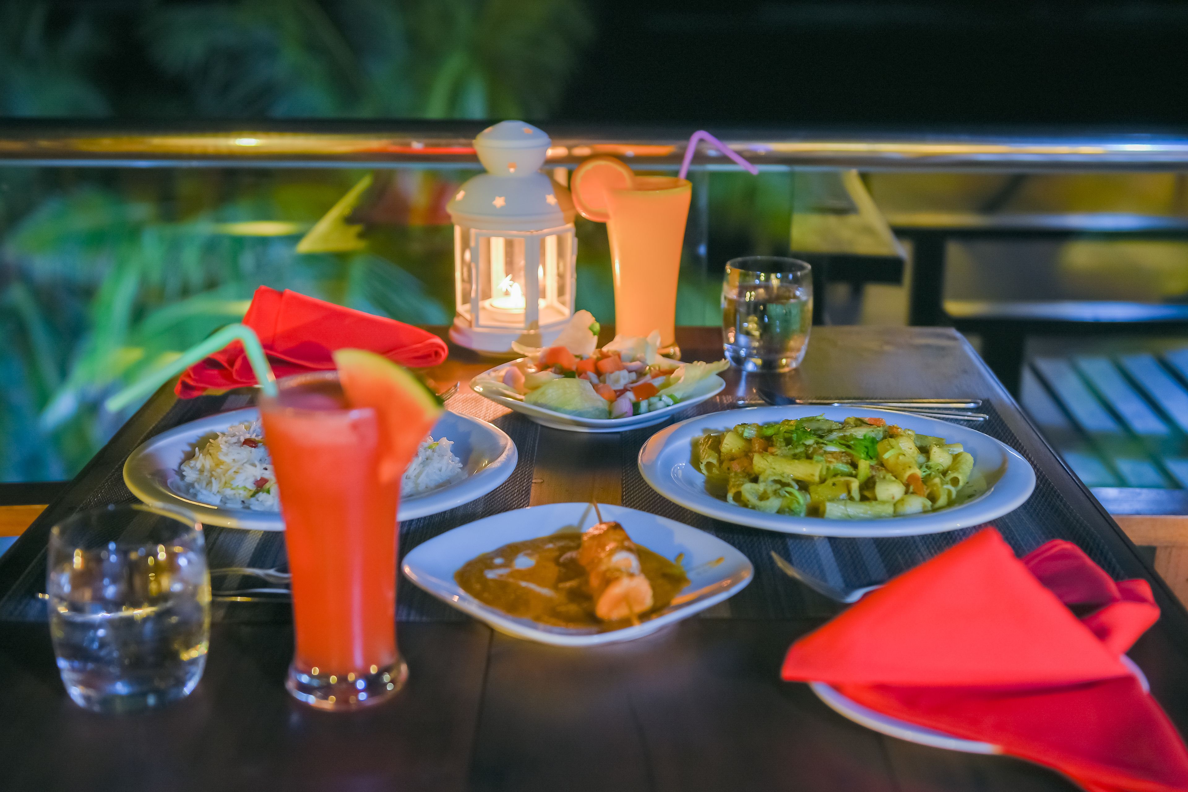Una mesa dispuesta con diversos platos, bebidas y un farol.
