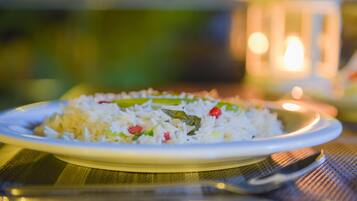 Un plato de arroz con verduras sobre una mesa, con una vela al fondo.