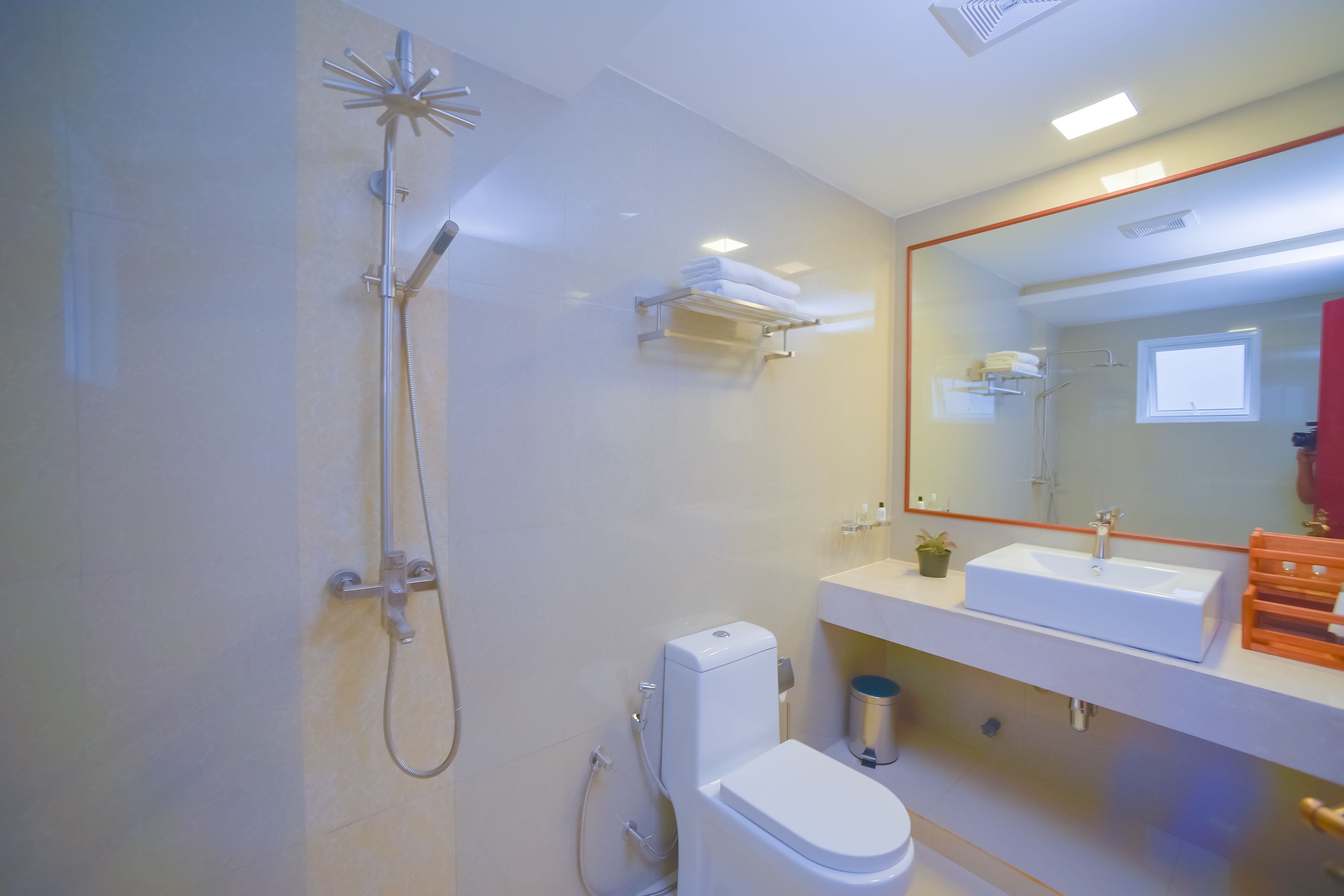 Un baño moderno con ducha, inodoro, lavamanos y espejo.