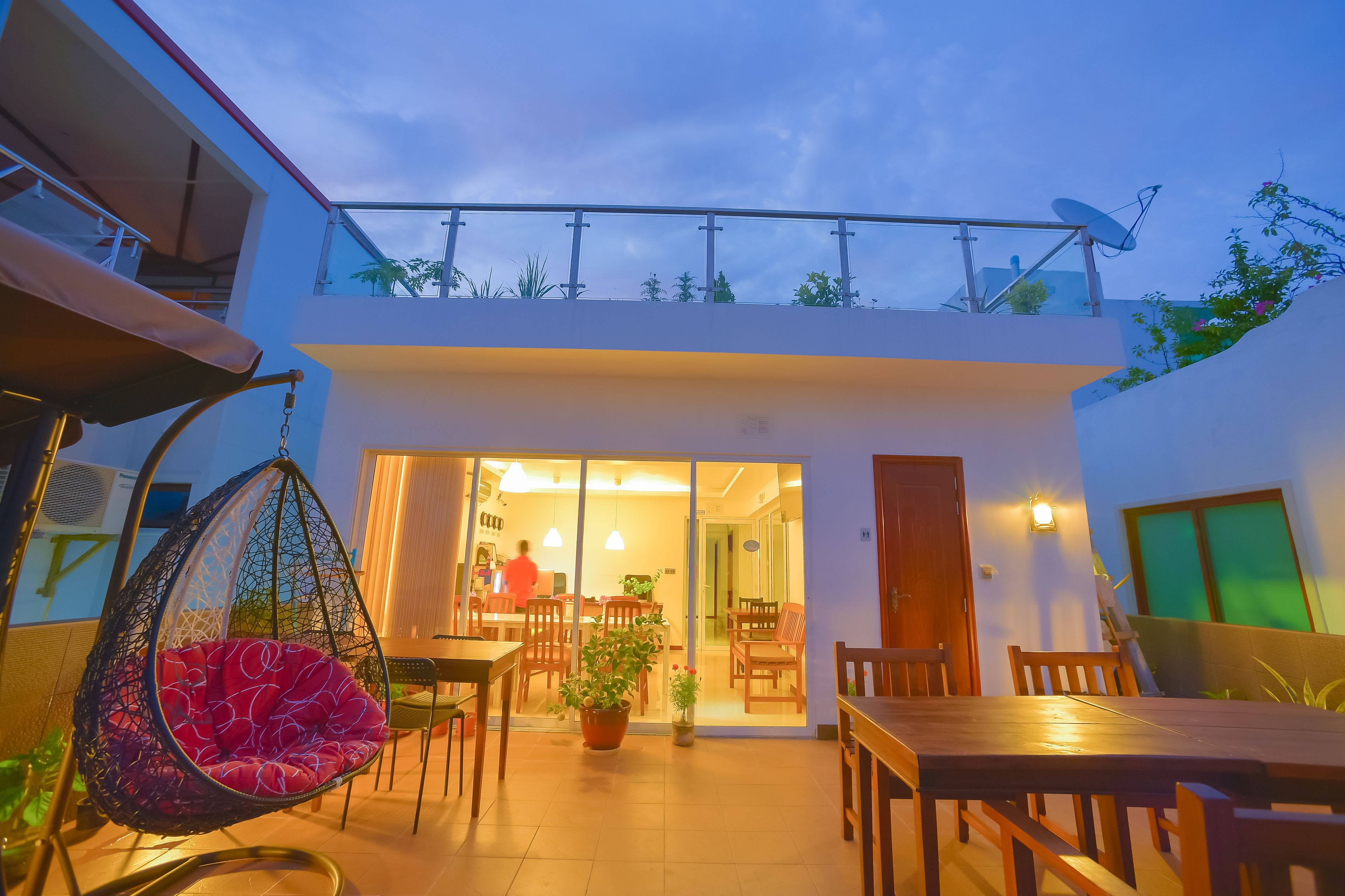 A modern house with a dining area, a hanging chair, and a potted plant.