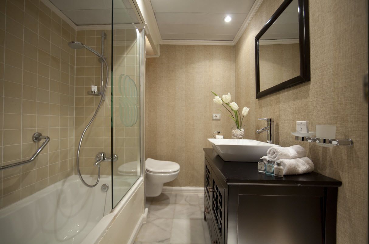 A modern bathroom with a glass-enclosed shower, a white toilet, a vanity with a sink and mirror, and a vase with white flowers.