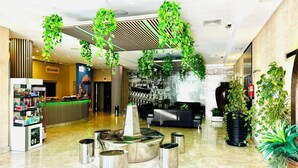 A lobby with a reception desk, a reception area, a seating area, and a water feature. - Hotel La Cantueña (Fuenlabrada)