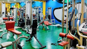A gym with various exercise equipment, a green rubber floor, and a mirror on the wall. - Hotel La Cantueña (Fuenlabrada)
