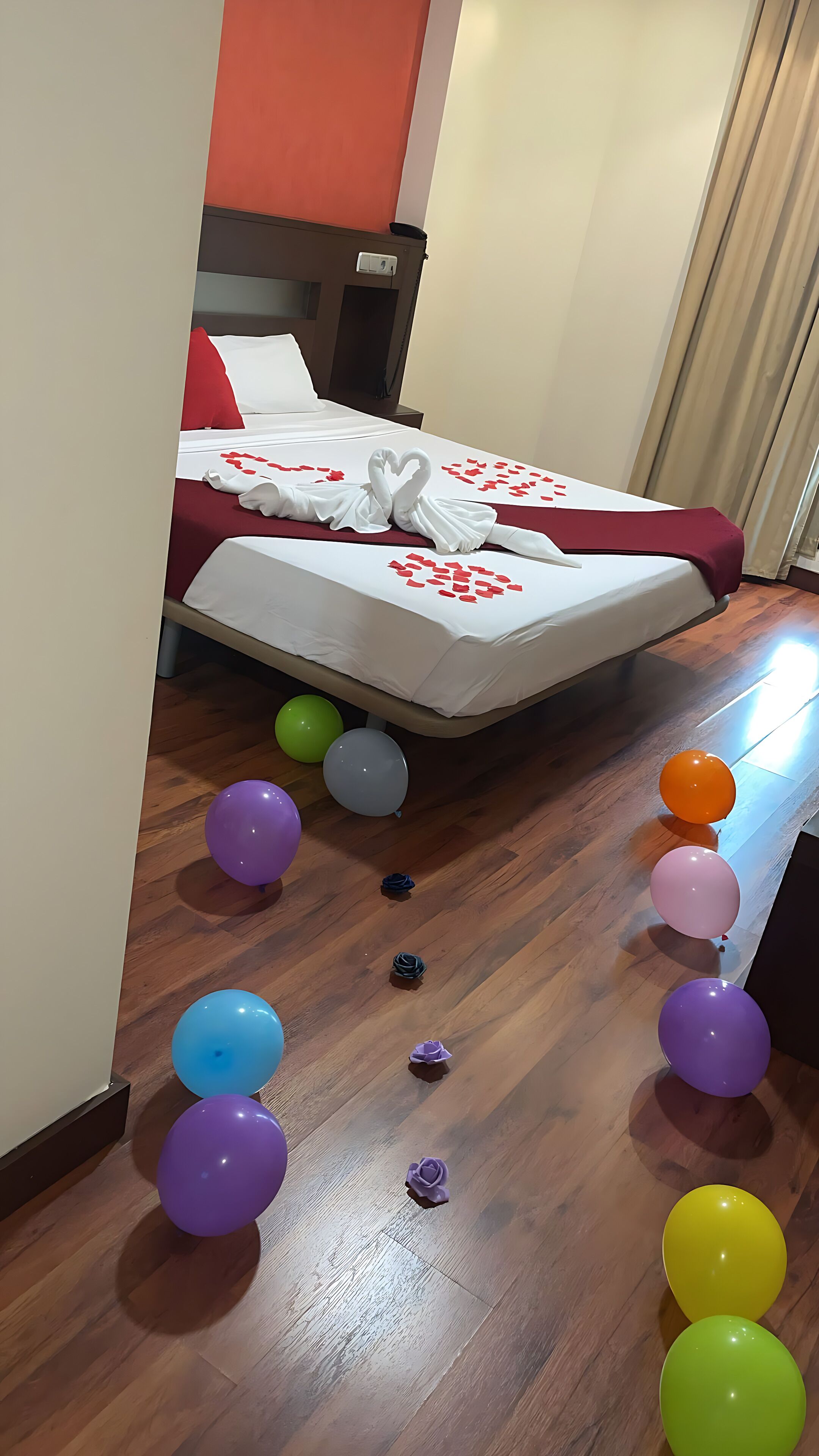 Una habitación de hotel con una cama, suelo de madera y globos.