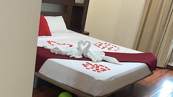 Quarto de hotel com cama, piso de madeira e balões.