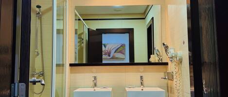 A modern bathroom with two sinks, a shower, and a toilet.