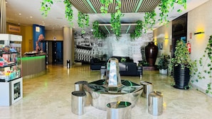 A modern lobby with a reception desk, seating area, and decorative plants. - Hotel La Cantueña (Fuenlabrada)