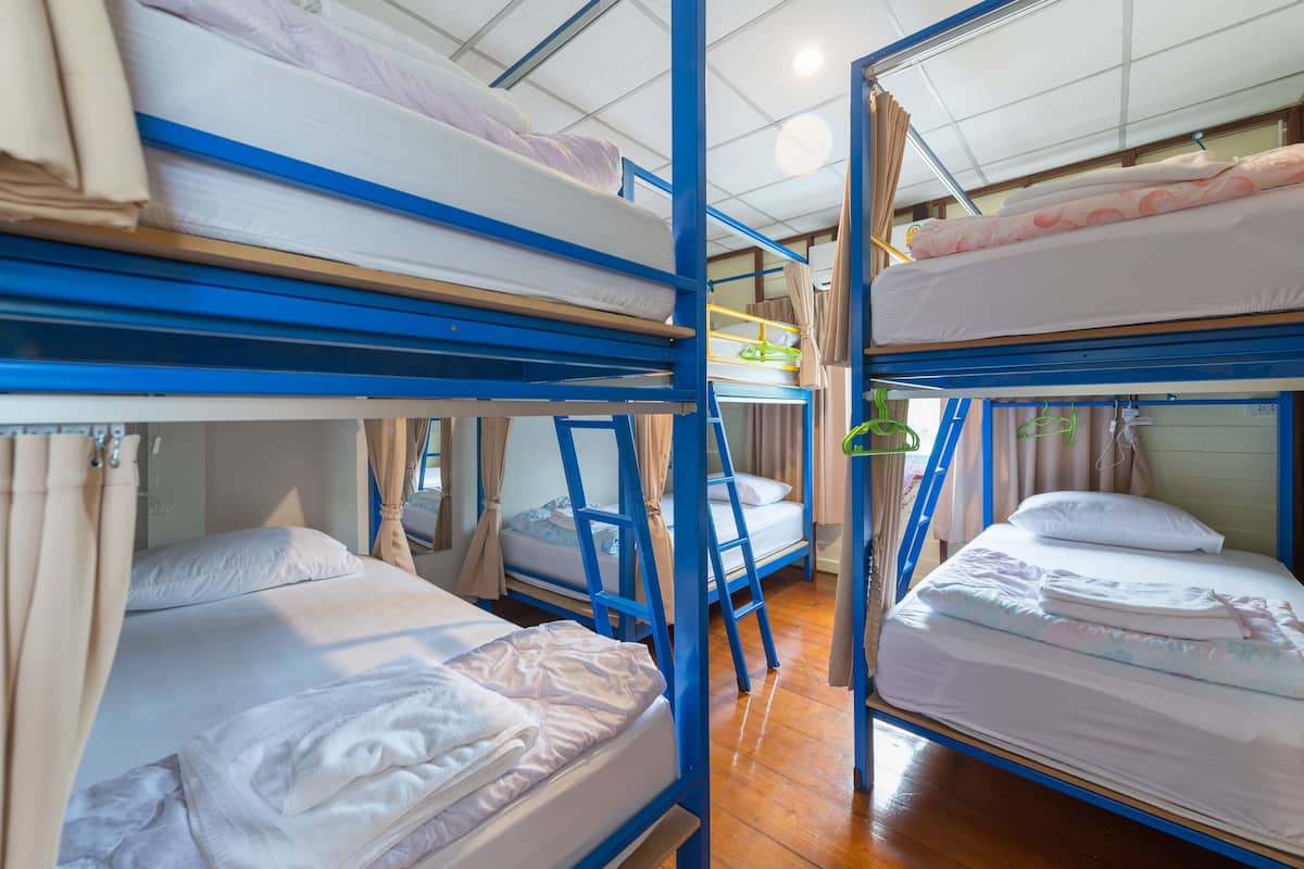 Ein Schlafsaalzimmer mit Etagenbetten, Holzboden und Vorhängen.